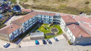Un hotel a più piani con cortile interno, parcheggio e vista sull'oceano.