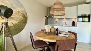 Una cucina moderna con mobili bianchi, un tavolo rotondo in legno e un lampadario in vimini.