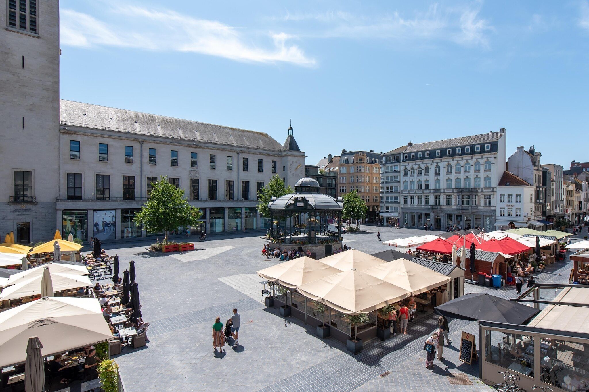 A public square with outdoor seating, a central fountain, and surrounding buildings.