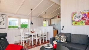 A cozy living room with a sofa, a coffee table, and a dining area with chairs and a table. - 4 Star Holiday Home in Hejls (Hejls)