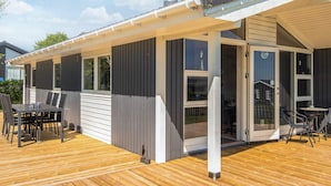 A modern house with a covered patio, large windows, and a chimney. - 4 Star Holiday Home in Hejls (Hejls)