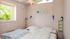A bedroom with a bed, a window, a star-shaped hanging light, and a shelf with a picture. - 4 Star Holiday Home in Hejls (Hejls)
