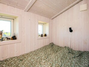 Una habitación con paredes de madera, una ventana y una cama con colcha estampada.