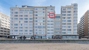 A multi-story hotel with a curved facade, large windows, and a beach view. - Apartment in Ostend with Stunning Sea View (OSTEND)