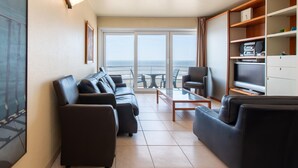 A modern living room with a sofa set, a coffee table, and a TV stand. - Apartment in Mariakerke with Stunning Sea Views (OSTEND)