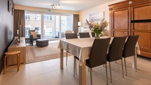A hotel room with a dining area, a sofa, a small table, and a view of the outside. - Apartment by the Beach in Ostend with Terrace (OSTEND)