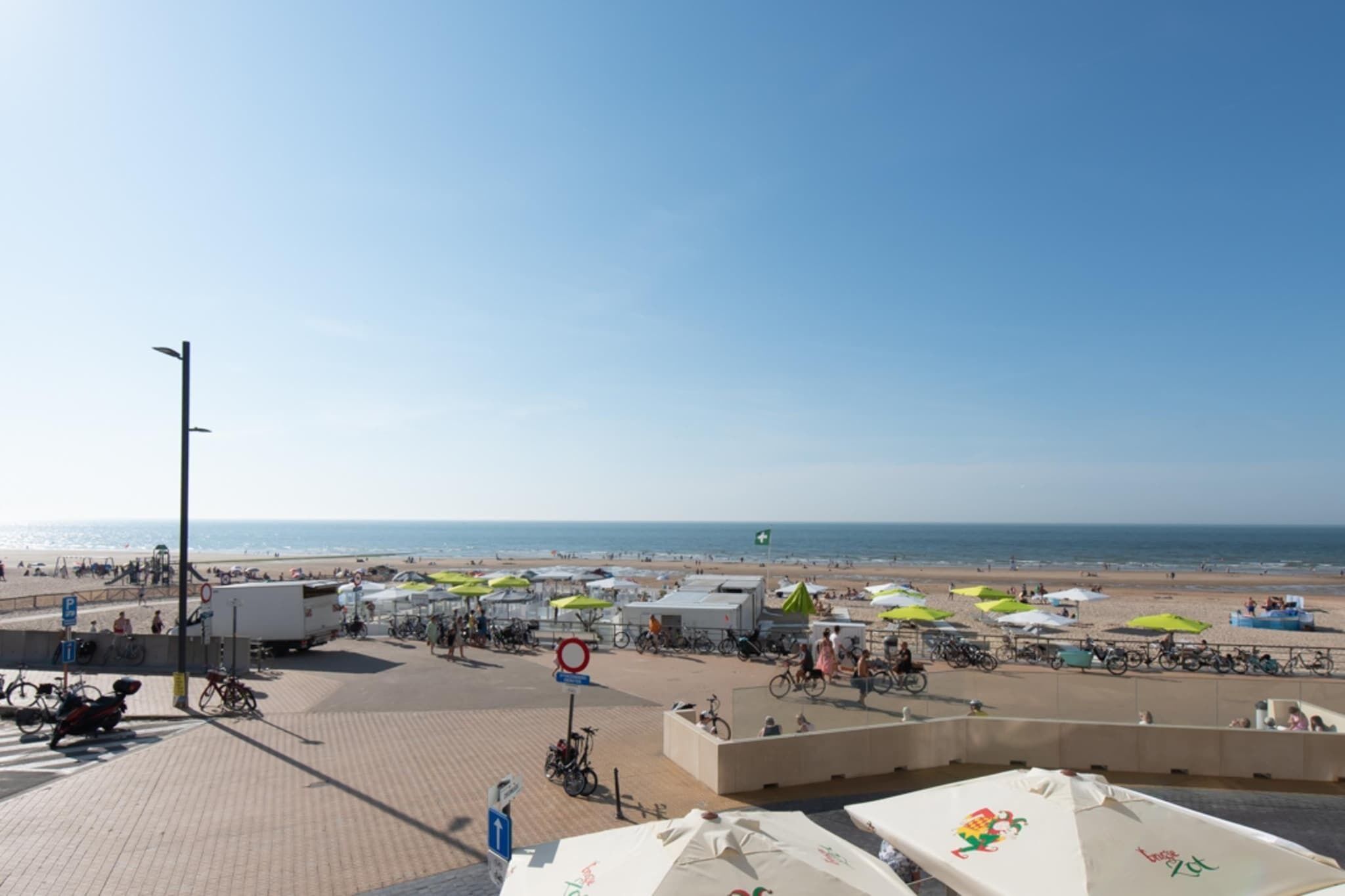 A beachside area with umbrellas, bicycles, and beachgoers.