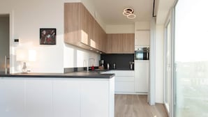 A modern kitchen with white cabinetry, a central island, and a large window providing natural light.