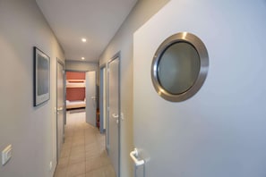 A hallway with a bunk bed, a round mirror, and a door with a handle.