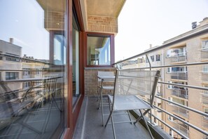 A balcony with a glass door, a small table, and a chair. - Apartment in Ostend near the beach (OSTEND)