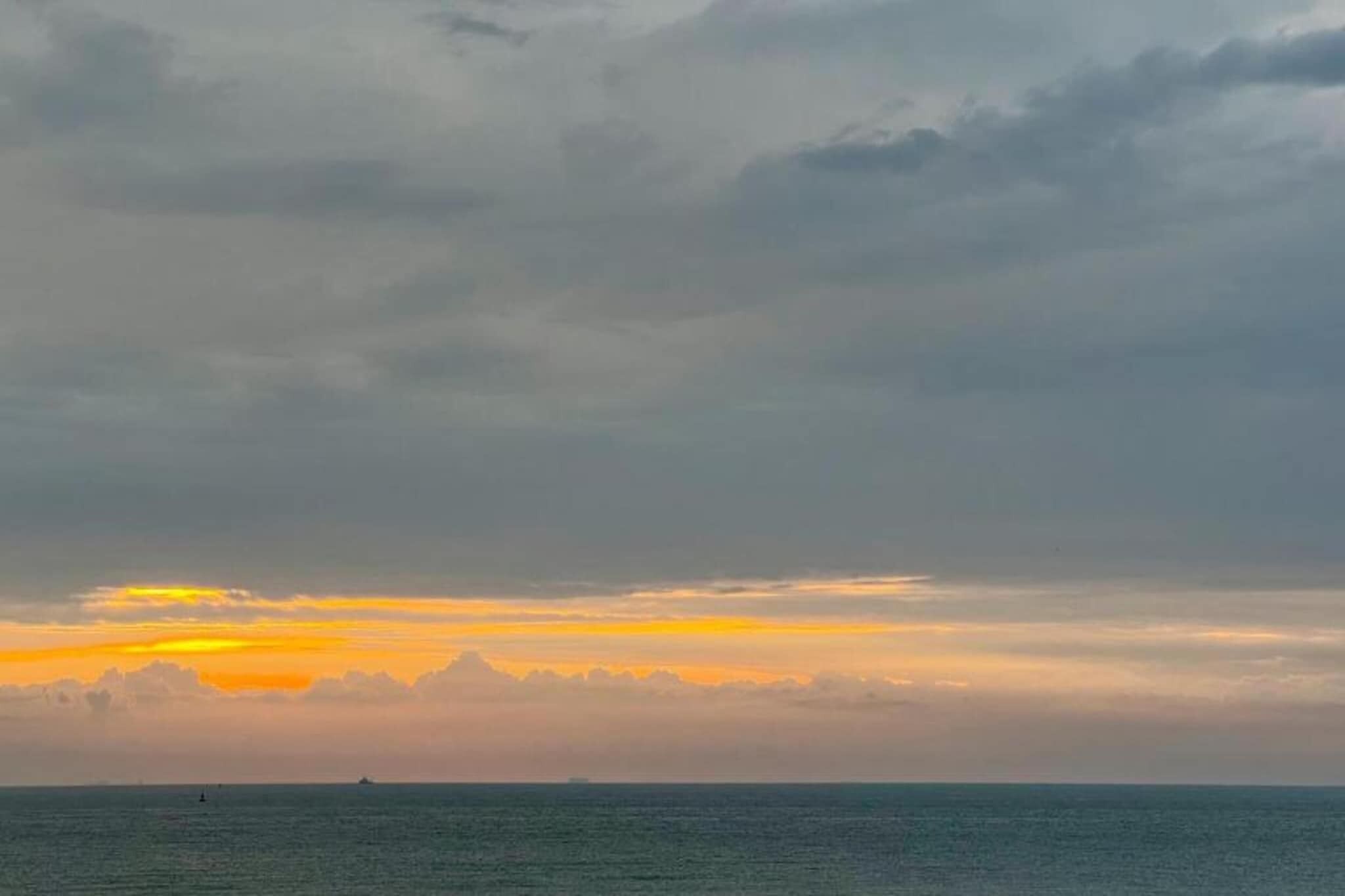 A sunset over a body of water with a distant landmass.