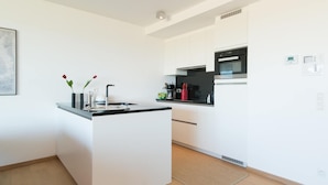 A modern kitchen with white cabinetry, a central island, and a stainless steel oven. - Apartment in Oostende near Beach & Dunes (OSTEND)