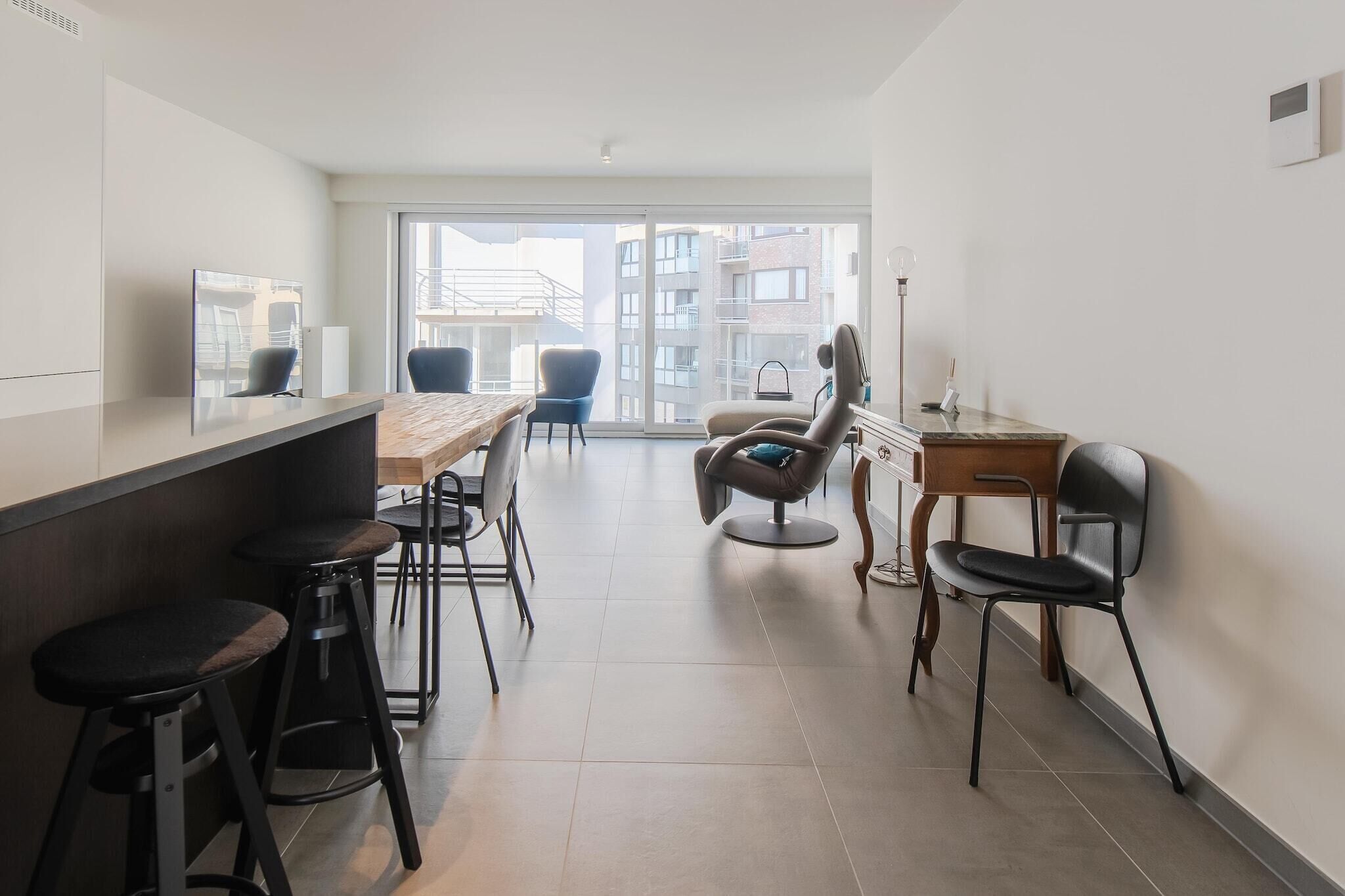 A modern kitchen with a wooden countertop, bar stools, and a dining area with chairs.