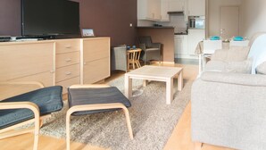Ein modernes Wohnzimmer mit Flachbildfernseher, einer Couch, einem Couchtisch und einem Essbereich mit Stühlen.
