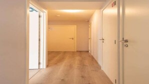 A hallway with wooden flooring and white walls.