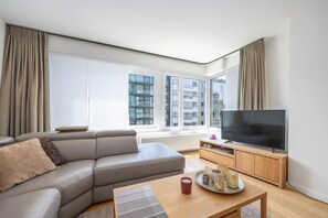 A modern living room with a sofa, a television, and a dining table.