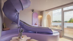 A modern interior with a curved purple slide, a seating area, and large windows offering a view of the outdoors. - Qi Meng Rainbow bridge branch (Shanghai)