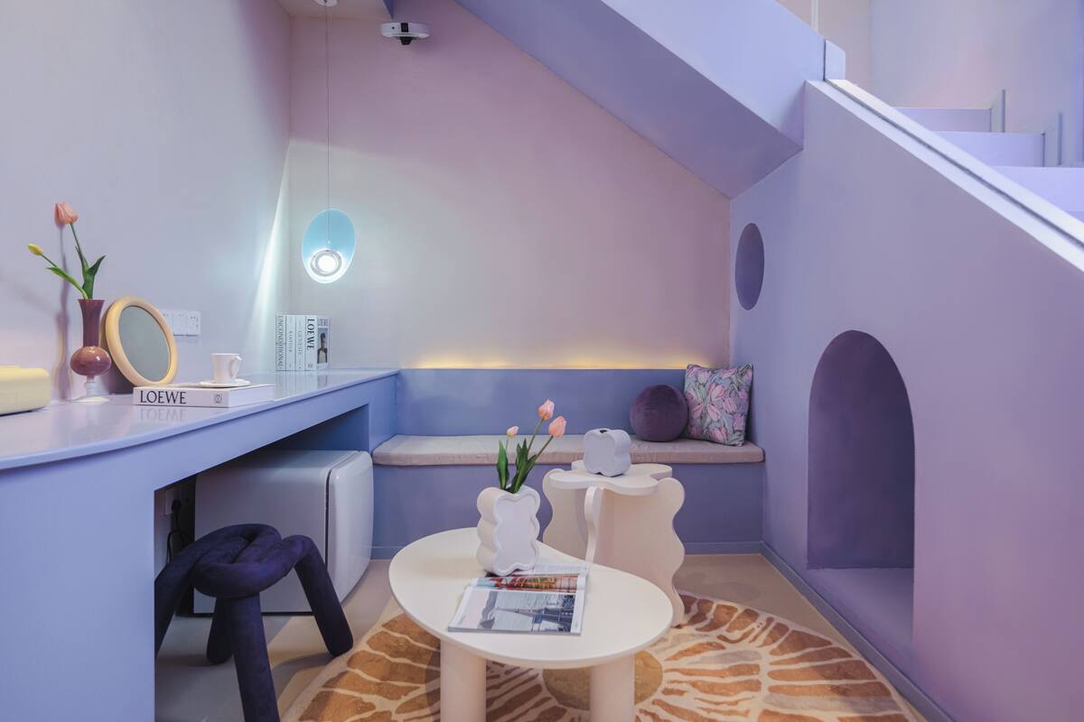 A modern, minimalist room with a sloped ceiling, a round table, and a seating area with a bench.