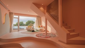 A modern interior with a curved staircase, a round seating area, and a view through large windows. - Qi Meng Rainbow bridge branch (Shanghai)