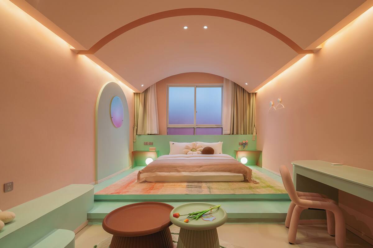 A bedroom with a bed, bedside tables, a desk, and a chair.