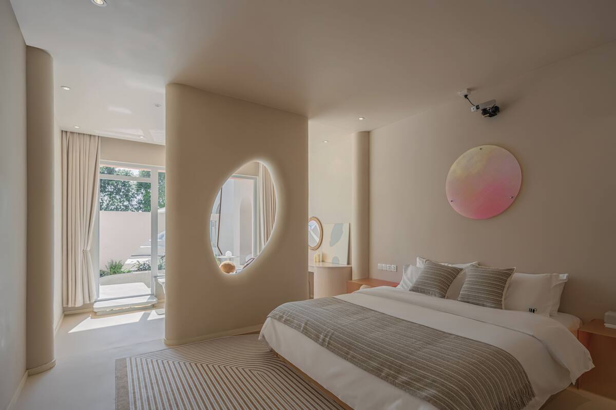 A modern bedroom with a large bed, a round mirror, and a circular wall decoration.
