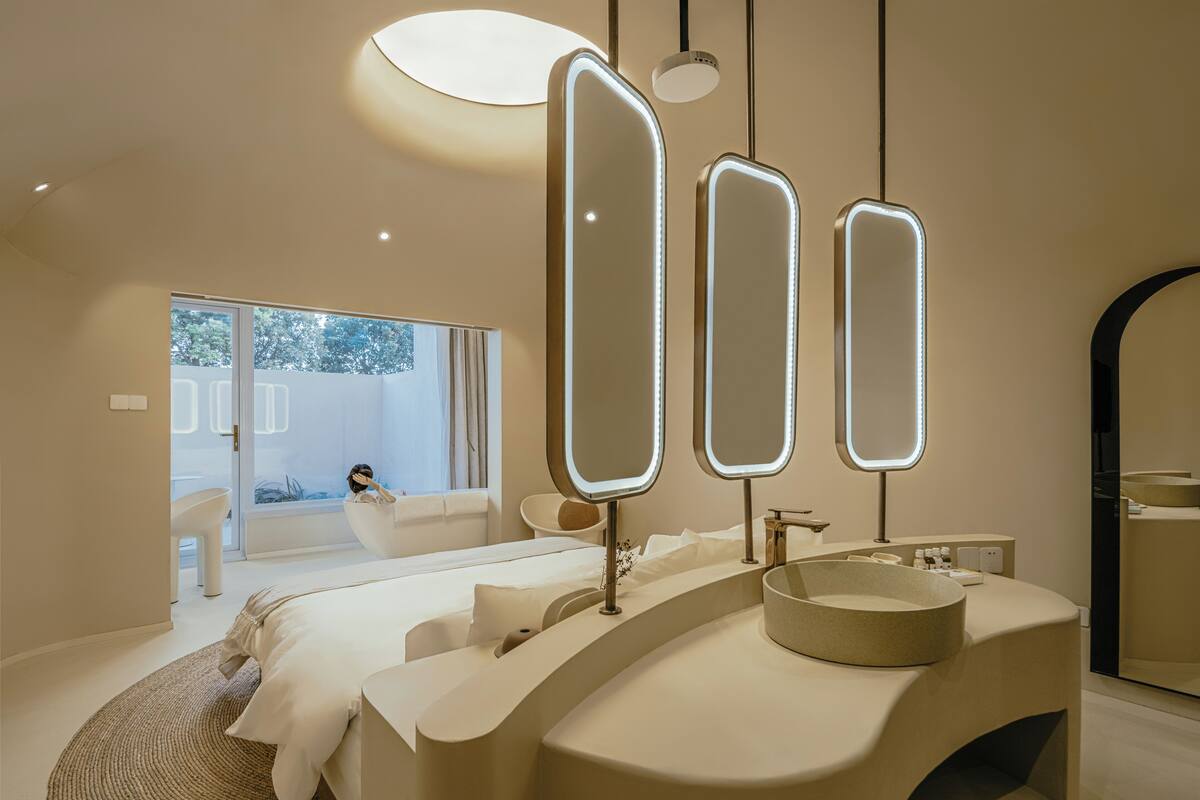A modern bathroom with a curved vanity, three mirrors, and a large window.