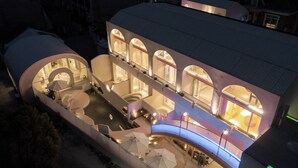 A modern hotel with a unique architectural design featuring arched windows and a spacious outdoor area with umbrellas. - Qi Meng Rainbow bridge branch (Shanghai)