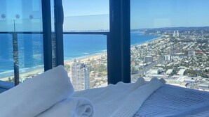 A hotel room with a large window offering a view of the beach and cityscape. - La Jolla Holiday Broadbeach (Broadbeach)