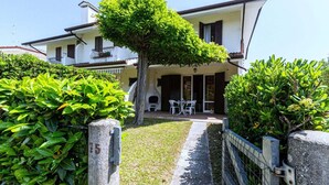 A two-story house with a paved driveway leading to a white gate. - Holiday Home in Porto Santa Margherita Beach (Porto Santa Margherita (VE))
