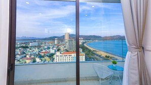 Ein Balkon mit Blick auf die Stadt, ein kleiner Tisch mit einer Pflanze und ein Stuhl.