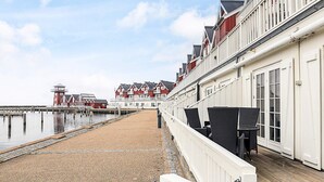 Ein Küstenhotel mit einer Holterrasse, Blick auf das Meer und einer Reihe von roten und weißen Gebäuden im Hintergrund.