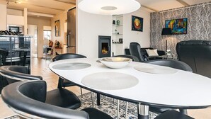 Ein stilvoller Essbereich mit einem weißen Tisch, schwarzen Stühlen und einer zentralen Leuchte.