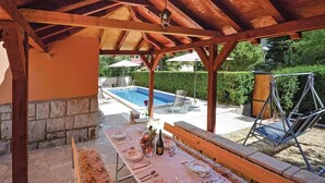 An outdoor covered patio with a pool, dining table set for four, and a swing chair. - Amazing home in Split with private swimming pool, can be inside or outside (Split)