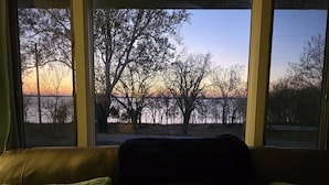 Une pièce avec vue sur les arbres et sur le coucher de soleil, grâce à de grandes fenêtres.