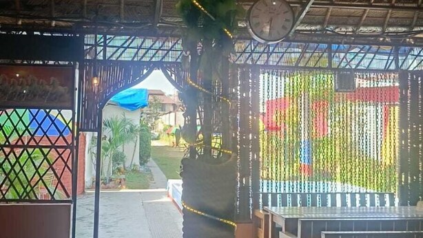 A covered outdoor area with a thatched roof, a decorative hanging element, and a view of the outside. - Krishna Raja Ji Downtown By GRB (Ganga Bhogpur Talla)