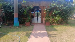 A pathway leading to a gated entrance with a bamboo fence and potted plants. - Krishna Raja Ji Downtown By GRB (Ganga Bhogpur Talla)