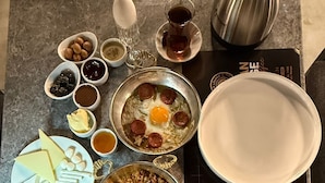 Una mesa con una variedad de platillos para el desayuno, incluyendo huevos, salchicha, queso y pan.