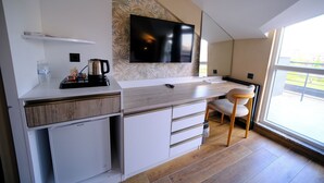 Una cocina moderna con televisor de pantalla plana, cafetera y refrigerador pequeño.