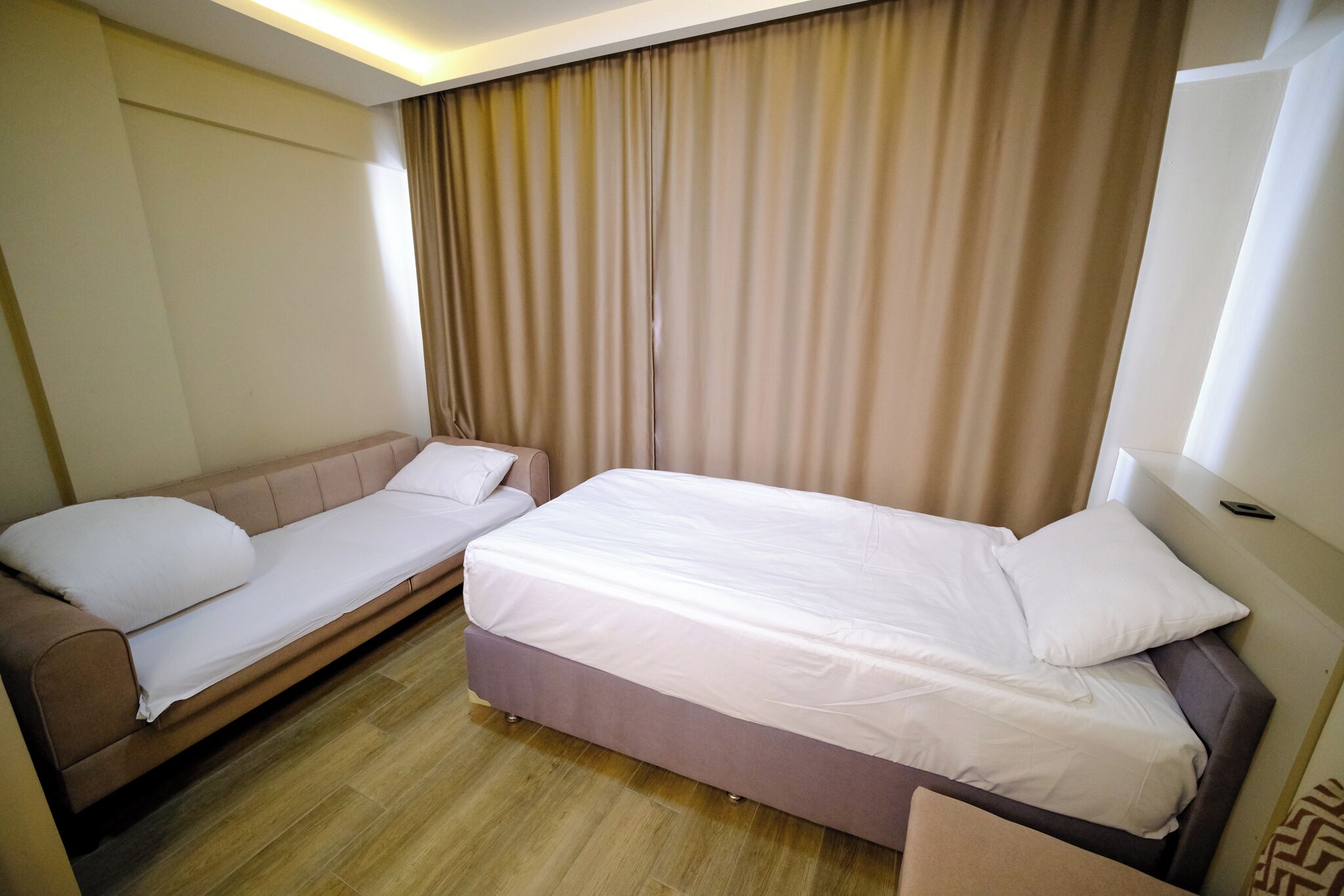A hotel room with a bed, a sofa, and a curtain.