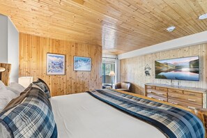 Ein Zimmer mit Holzwänden, einem Bett, einem Fernseher und zwei gerahmten Bildern an der Wand.