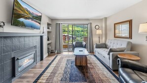 Un salon moderne avec une cheminée, un canapé, une table basse et un téléviseur fixé au mur.