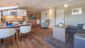 Une cuisine moderne avec des meubles blancs, un four à micro-ondes et un coin repas comprenant deux chaises et une table.