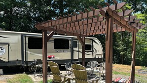 A recreational vehicle with a covered patio area, outdoor seating, and a fire pit. - Cozy Smoky Mtn RV with WiFi and Heat/AC near Cades Cove (Walland)