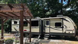 A recreational vehicle with a covered patio area, outdoor seating, and a fire pit. - Cozy Smoky Mtn RV with WiFi and Heat/AC near Cades Cove (Walland)