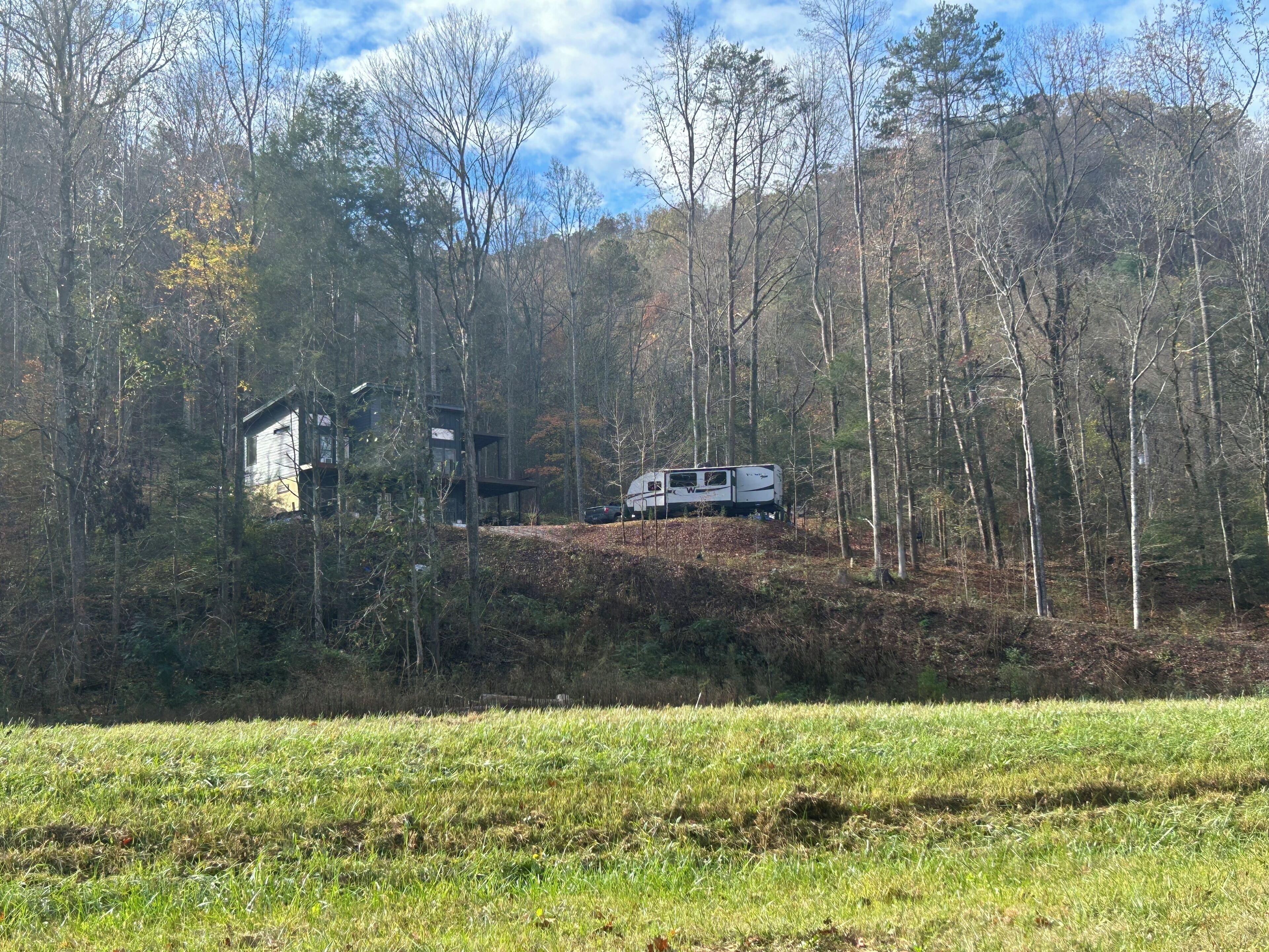 A remote cabin with a small attached structure, surrounded by dense forest.