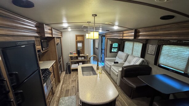 A compact RV interior with a kitchenette, a dining area, a seating area, and a small table. - Cozy Smoky Mtn RV with WiFi and Heat/AC near Cades Cove (Walland)