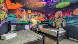 A bedroom with two beds, a nightstand, and a wall mural depicting space and a pizza planet theme. - Top Family Stay: Private Pool & Game Room (Four Corners)