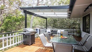 An outdoor patio with a grill, seating, and a table set for two.