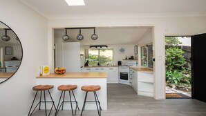 A modern kitchen with a central island, bar stools, and a view of the garden.