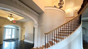 Una imponente escalera de diseño curvo, paredes blancas y un candelabro.